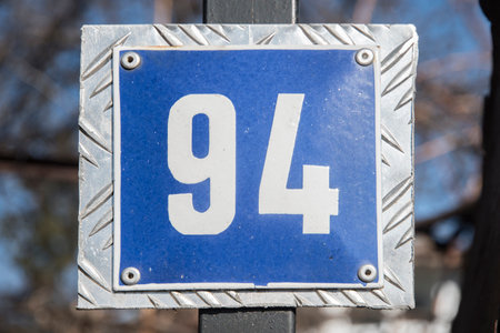 Weathered grunge square metal enameled plate of number of street address with number 94