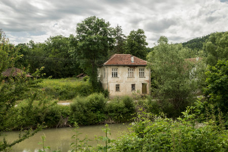 Rural landscape with abandoned house by a river in cloudy dayの写真素材