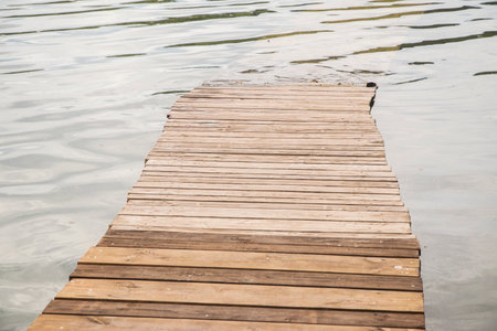 Wooden walkway on the lake with reflection in water background. Wooden boardwalk leading into lake...