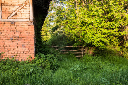 Old wooden fence in the village and old rural country brick houseの写真素材
