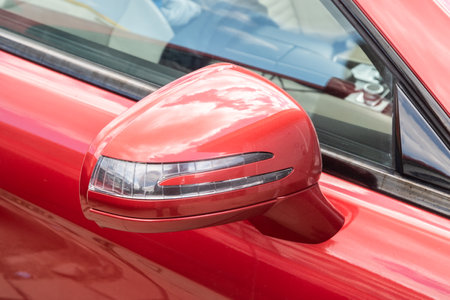 Side mirror of luxury red car closeup