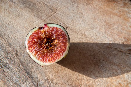 Ripe figs cut in half on wooden board surface closeup