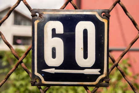 House number 60 (60) on a metal plate with a chain link fenceの写真素材