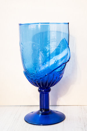 Broken blue glass on a white wooden background.の写真素材