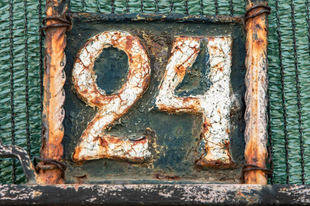 Old rusty metal plate with number 24. Close-up.
