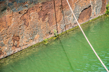 Close-up of a severely rusted, corroded hull of an old river cargo barge floating on calm, greenish waterの写真素材