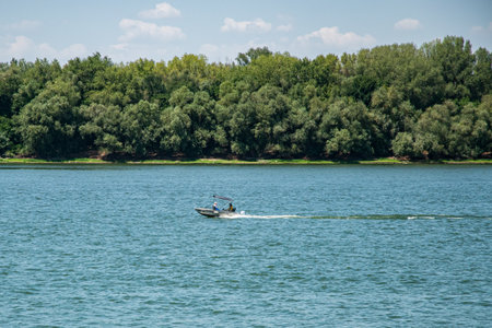 A small motorboat speeding across a wide river, leaving foamy white wake in its path