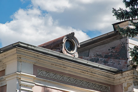 An ornate, beautiful old attic circular window on a historic European building, showcasing early...
