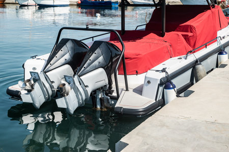 Close-up detail of outboard motor and propeller on docked marine boat, elevated above the water