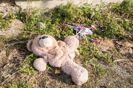 Abandoned teddy bear lying on the ground in the parkの写真素材