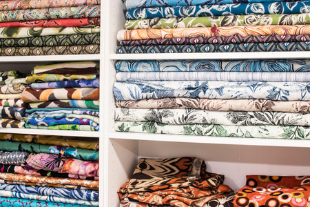 Shelves with neatly stacked patterned fabrics in tailoring atelier, textile selection and fashion...