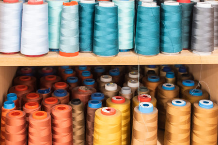 Shelves with colorful sewing thread cones in professional tailoring atelier, textile production and...