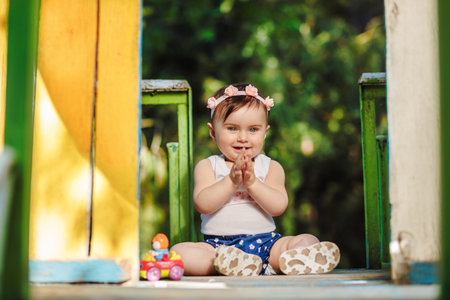 Cheerful eight months old baby in playground clapping her hands and laughingの写真素材