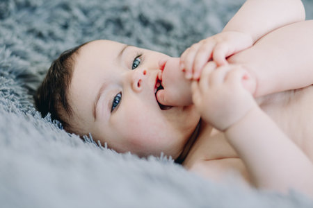 Cute baby with blue eyes sucking and playing with her toeの写真素材