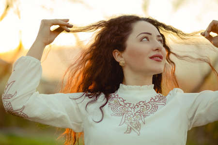 Lifestyle shot of curly hair beautiful girl in spring at sunset