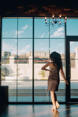 Elegant young woman standing in front of sliding glass door in luxury restaurantの写真素材