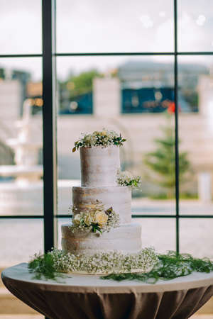 Elegant sweet white engagement cake in front of the modern windows with blurred backgroundの写真素材