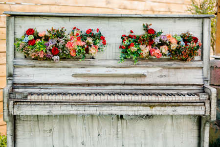 Outdoor decorative retro white piano with flower ornaments and water cascade.Decorative piano outdoor photoshoot.の写真素材