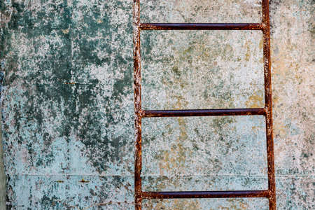 Closeup of rusty corroded metal ladder in abandoned place in front of textured background. Photoshoot in abandoned placeの写真素材