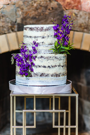 Vertical shot of tasty birthday cake decorated with lavender flower in banquet hall in front of the fireplaceの写真素材
