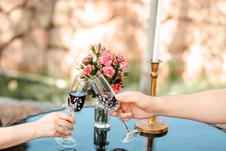 Lovely couples hands moving towards each other holding glasses and touching each other in a gentle clinkの写真素材