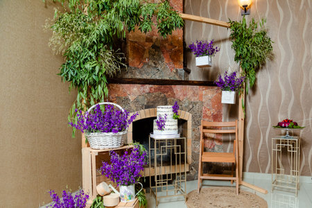 A birthday interior decoration with lavender flowers and a tasty cake in front of the fireplaceの写真素材
