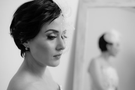 BW close-up of elegant bride in front of the mirror waiting for the groomの写真素材