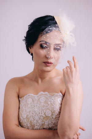 Vetical portrait of elegant bride with beautiful eyes in veil hat posing for cameraの写真素材