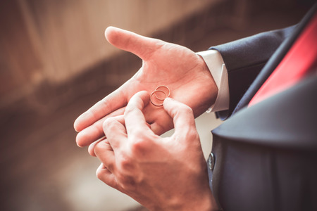 A man in a suit holding in hands his wedding rings