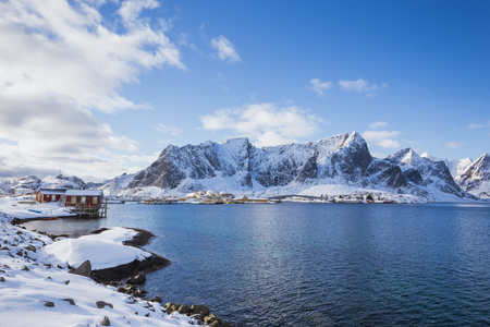 A small settlement by the sea in a quiet bay with high mountains in the background during the winter season in Norway in the Lofoten Islands.の写真素材