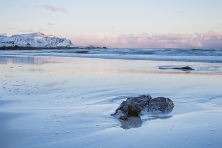 A magnificent panorama of the ocean coast, the waves wash the sandy coast, a winter landscape with mountains in Norway on the Lofoten Islandsの写真素材