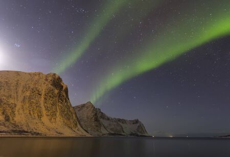 Northern lights at night against the backdrop of beautiful mountains by the ocean at a time of winter in Norway in the Lofoten Islandsの写真素材