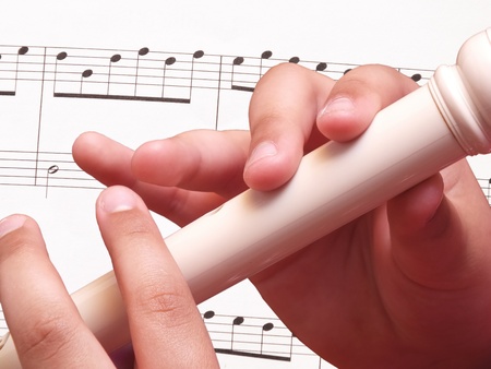 Child playing on white recorder の写真素材