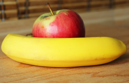 Red apple and yellow banana on the wooden tableの写真素材