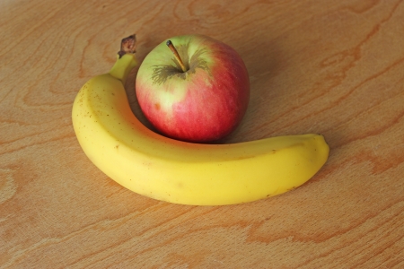 Red apple and yellow banana on the wooden tableの写真素材