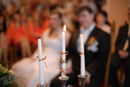 Three candles on a weding wit the happy couple in the backgroundの写真素材