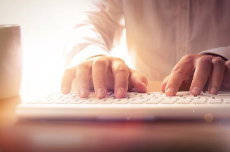 Closeup of man's hands typing on keyboard. Image can be used for background, website banner,...