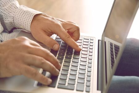 Man's hands typing on laptop keyboard.