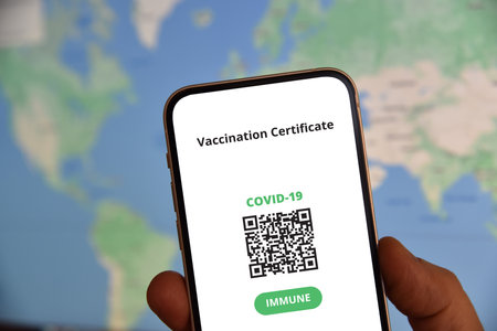 Mobile phone  with digital certificate of vaccination against Covid-19 in front of the world map. Travel and tourism concept during coronavirus pandemic.の写真素材