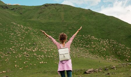 Curly young woman enjoying the view in the top of mountain on a hot summer day. Lifestyle concept....