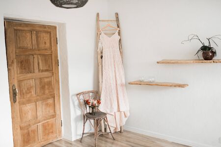 Wedding interior. Charges the bride at the hotel. Wedding photography. The brides dress hangs near the window. loft style, bride fees. Morning Bride Fees. Bridal morning details.の写真素材