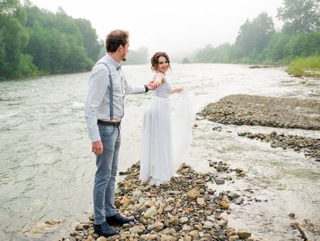 Emotions bride and groom. Just merried. wedding couple. Happy bride and groom on their wedding walking and holding hands. bride and groom in mountains, beautiful nature, landscape, fogの写真素材