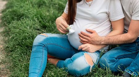 Cropped image of pregnant woman holding baby shoes with her husband