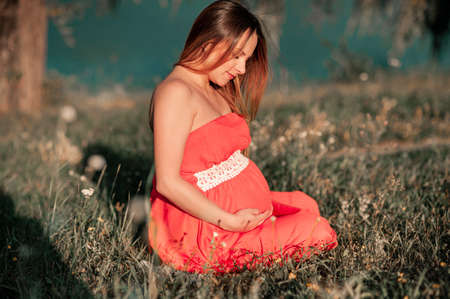 Attractive Pregnant woman outdoors with flowers on the beach. Pregnant girl portrait, healthy...