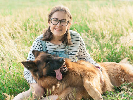 Portrait of young beautiful woman sitting and hugging her German Shepherd dog. Happiness and...