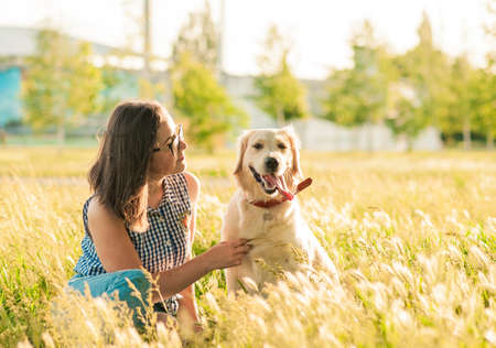 Portrait of young beautiful woman lying and hugging her Labrador retriever dog. Happiness and...