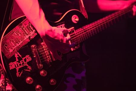 An electric guitar being played live on stage, with very red light.の写真素材