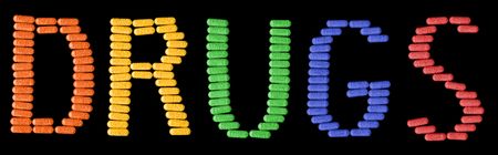 Colourful pills spelling the words DRUGS isolated on black.の写真素材
