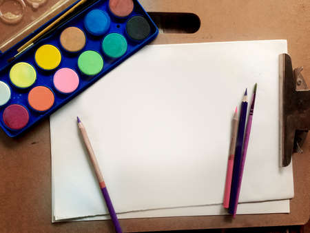 Top view close-up photo of sketchbook, palette, watercolor, colored feather, rustic wood background. Copy space for text. Natural, boho, ethnic or hipster vintage mock up.の写真素材