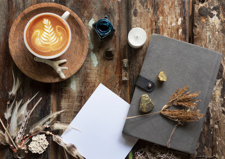 Rustic wooden background with boho chic style decorations: dreamctcher, cup of cappuccino, notebook and paper stars. Copy space for text. Natural, rustic, ethnic or hipster vintage mock up. Top view.の写真素材
